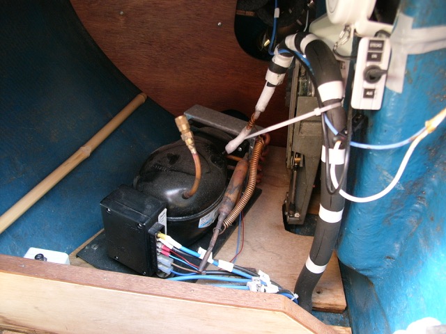 ET RIGTIGT køleskab ombord på en Bianca 27, kræver en kompressor, der kan levere kulden. Den passer sig selv og behøver ikke at være specielt nemt tilgængelig. Denne er installeret i styrbord kistebænk agterude lige bag gashåndtag og kabel. Et halv-skot forhindrer, at andet materiel ruller hen mod kompressoren, Set på Holnis fra Flensborg.